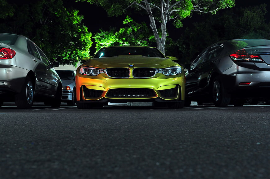 Low angle night shot of yellow BMW M4 in parking lot