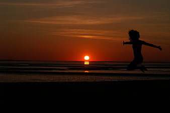 Silhouette of Woman Jumping on Beach at Sunset