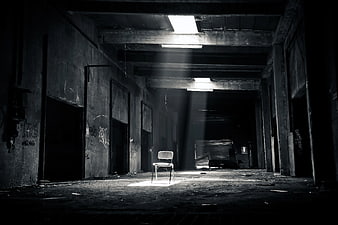 Lone Chair in Abandoned Warehouse with Dramatic Light Beams