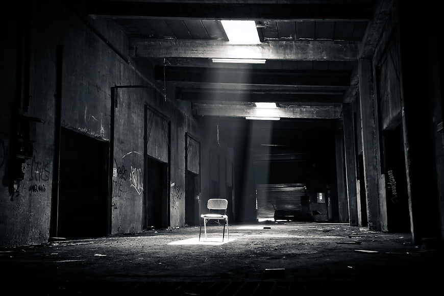 Lone Chair in Abandoned Warehouse with Dramatic Light Beams