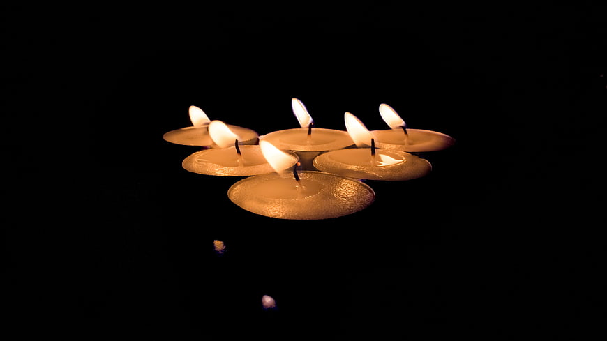 Floating Tea Light Candles on Black Water Surface