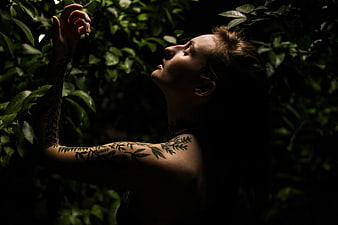 Woman with Leaf Tattoos in Dark Forest Foliage
