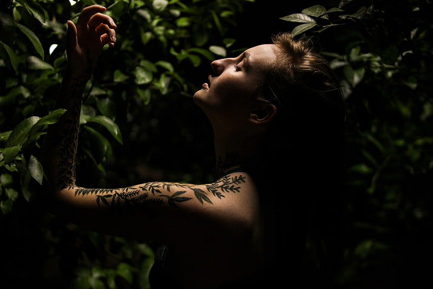 Woman with Leaf Tattoos in Dark Forest Foliage
