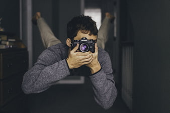 Young man taking a photo with a Nikon camera in a dark room