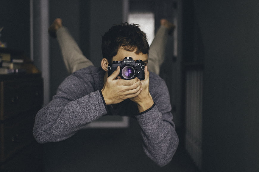 Young man taking a photo with a Nikon camera in a dark room