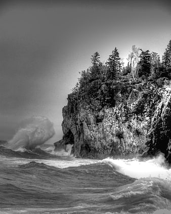 Dramatic Black and White Photo of Stormy Waves Crashing Against Rocky Cliff