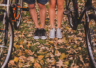 Couple's Feet in Sneakers Standing on Autumn Leaves with Bicycles