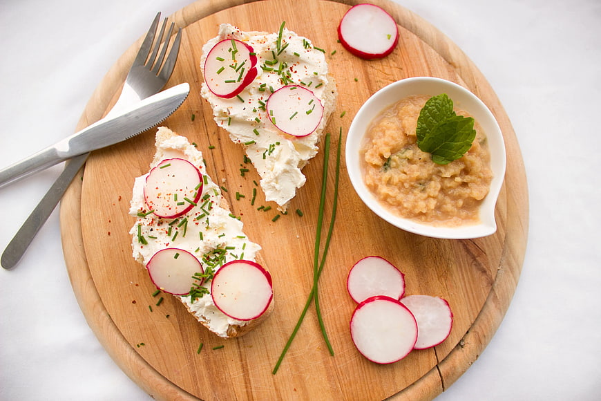 Bruschetta with cream cheese, radish, and chives on wooden board