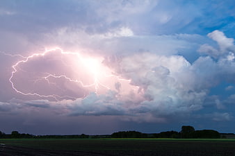 Dramatic Lightning Strike Over Dark Agricultural Fields at Dusk