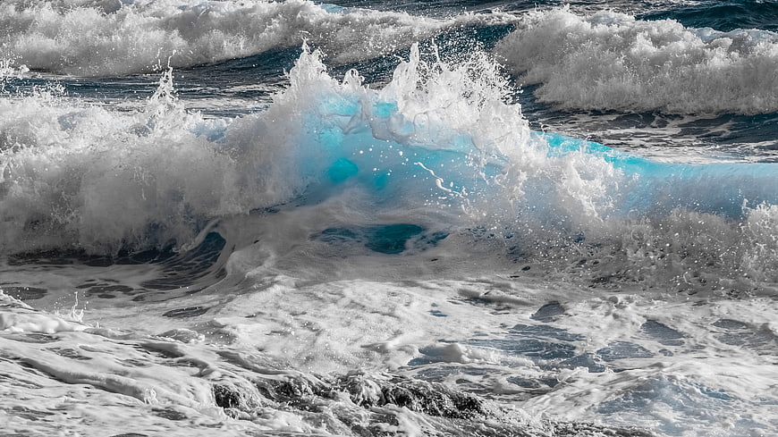 Powerful turquoise ocean wave crashing with white sea foam