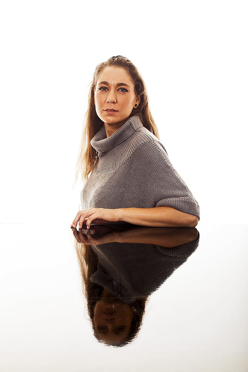 Professional young woman in gray turtleneck sweater with reflection on white background