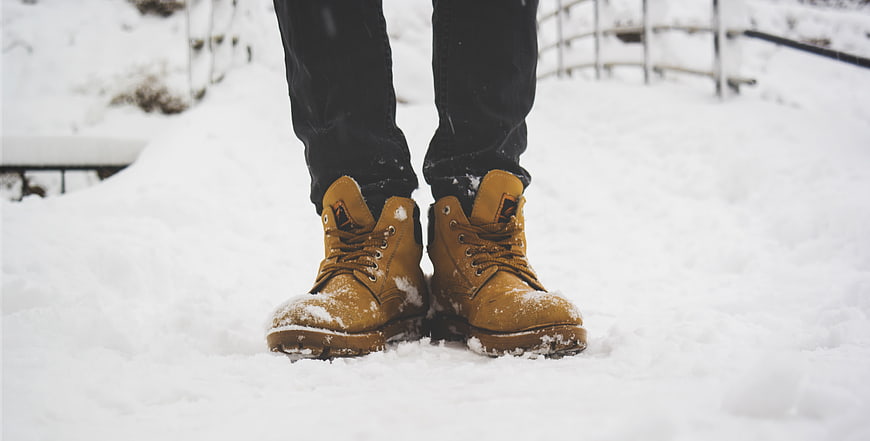 Close-up of tan work boots standing in deep snow