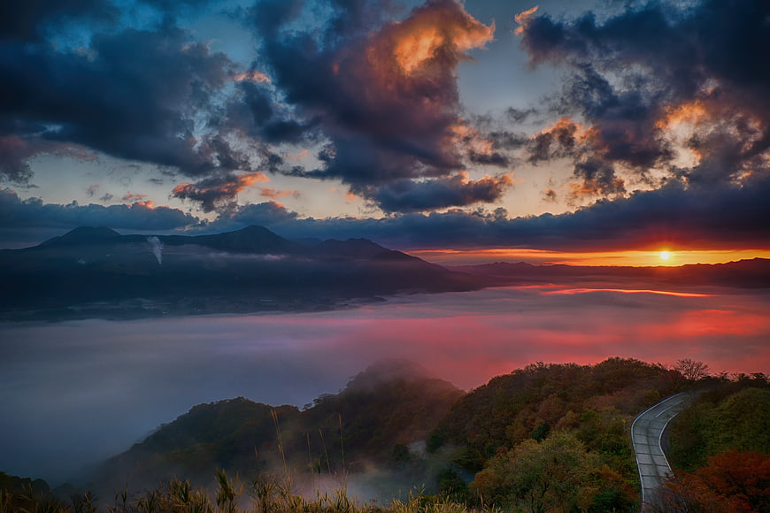 Dramatic Sunset Over Sea of Clouds and Mountain Road