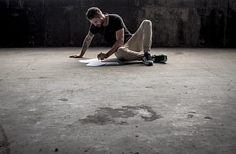 Man drawing on paper in empty industrial concrete room