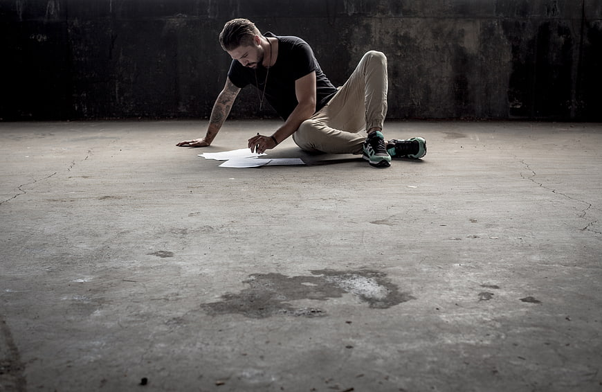 Man drawing on paper in empty industrial concrete room