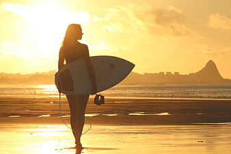 Silhouette of Woman with Surfboard on Beach at Golden Hour
