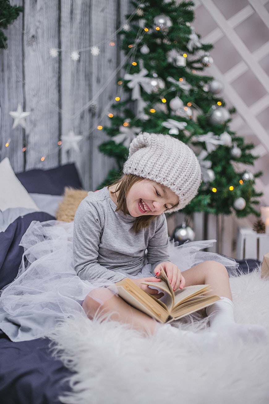 Happy Girl Reading Book by Christmas Tree
