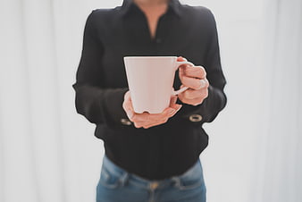 Woman holding white coffee cup in black shirt