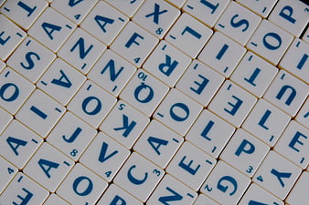 Scattered Scrabble Tiles with Blue Letters on White Background