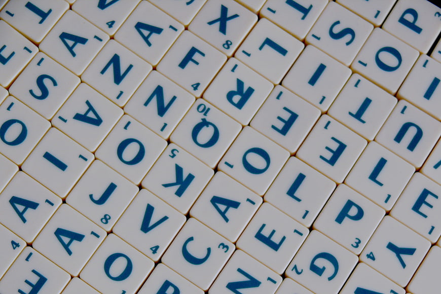Scattered Scrabble Tiles with Blue Letters on White Background
