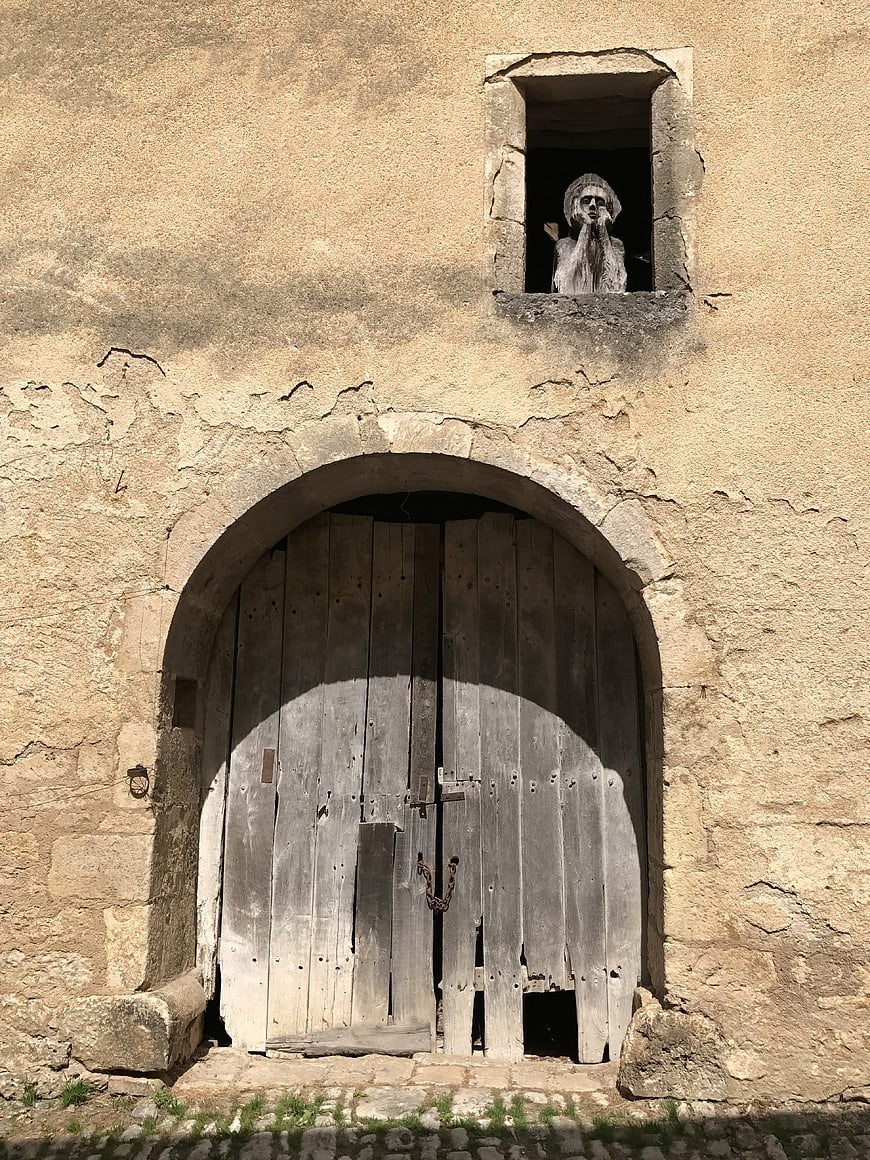Rustic stone facade with arched wooden door and statue niche