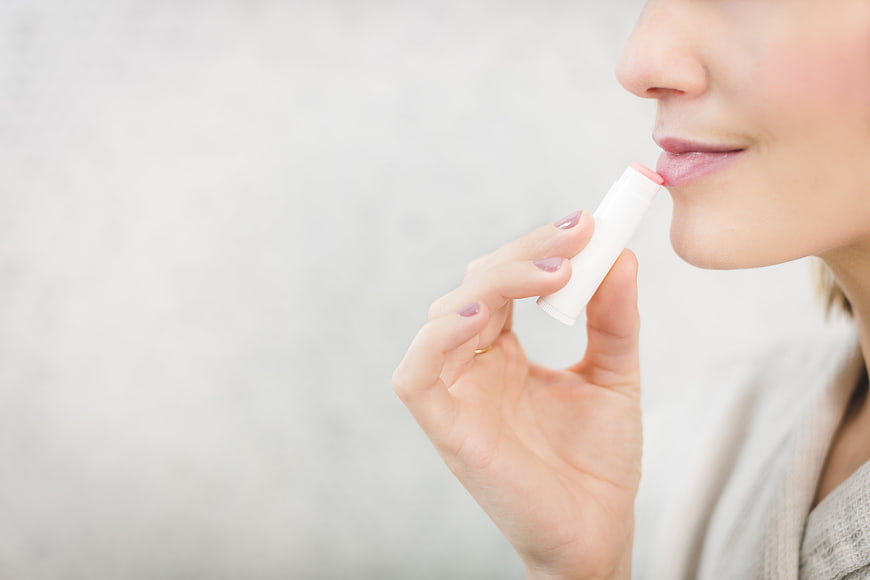 Woman applying lip balm close-up with copyspace
