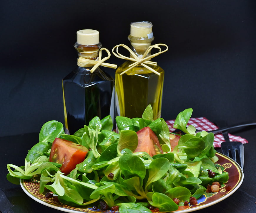 Fresh green salad with tomatoes, olive oil, and vinegar bottles