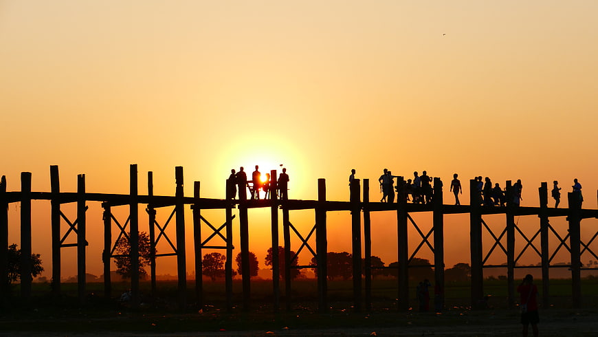 Silhouette of people on U Bein Bridge at sunset