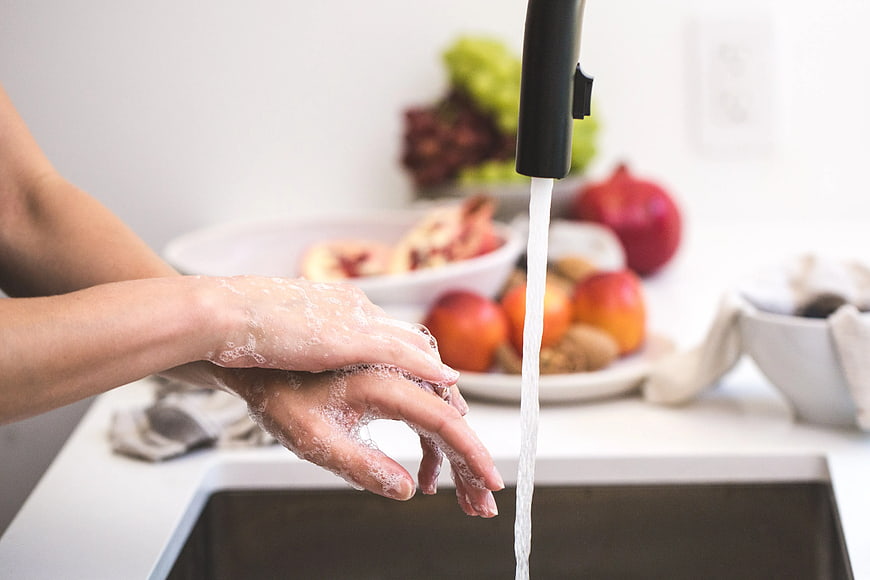 Close-up of hands washing with soap under running water