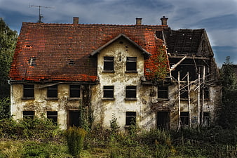 Dilapidated Abandoned House With Red Roof And Overgrown Vegetation