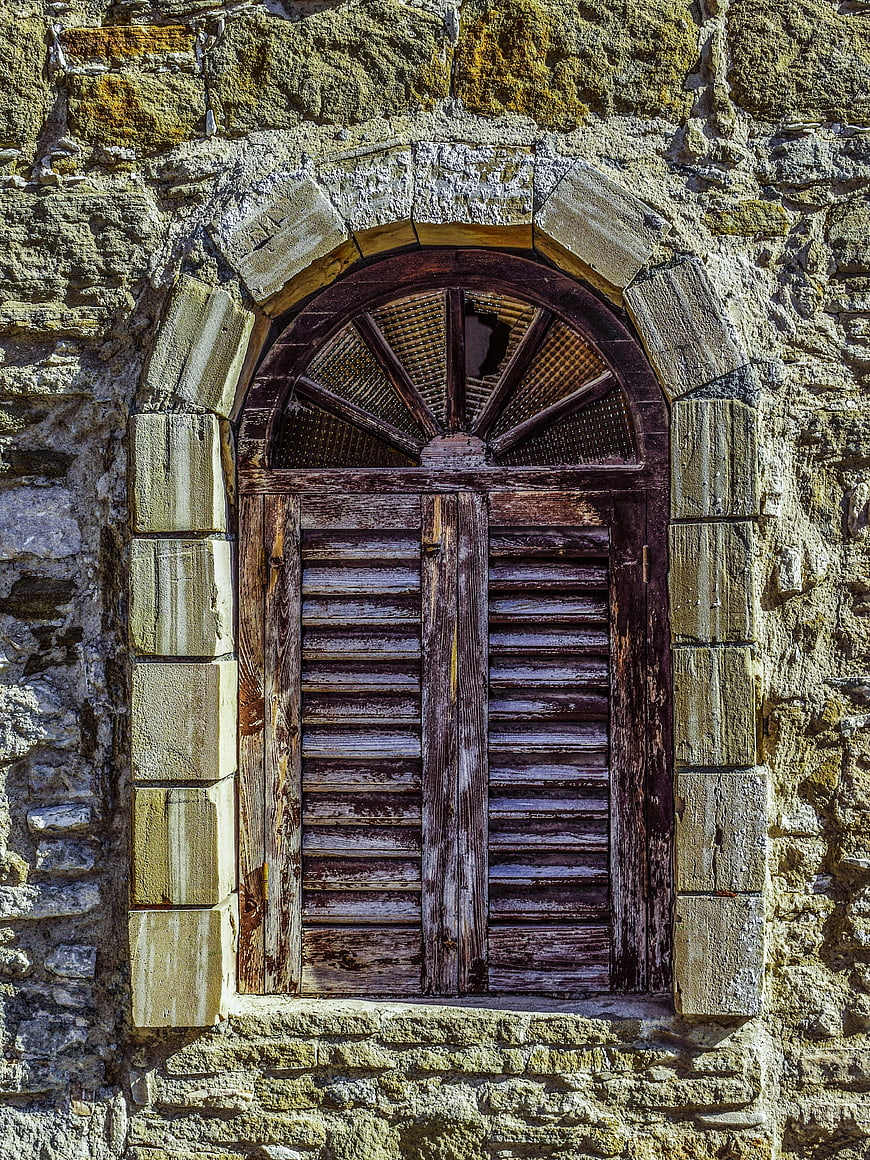 Weathered wooden window in old stone wall