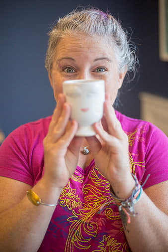 Senior woman holding white face mug indoors