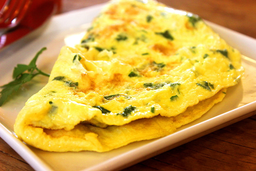 Golden herb omelet on white rectangular plate