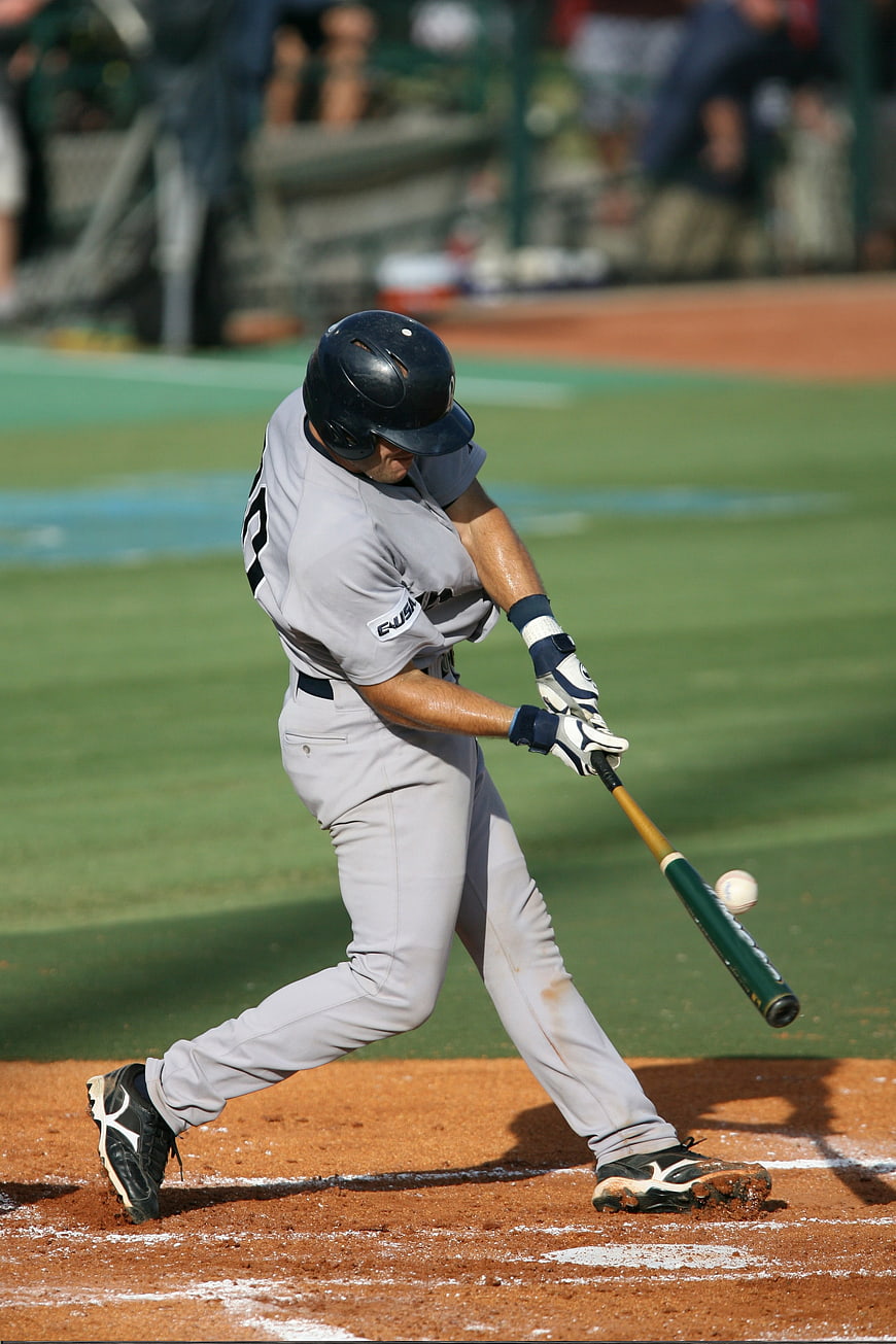 Baseball Player Swinging Bat at Ball on Field