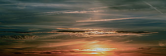 Dramatic sunset sky with layered clouds and contrails