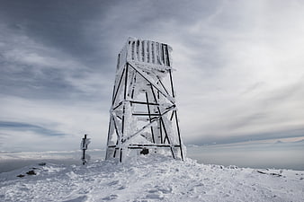 Snow-covered metal tower on mountain peak
