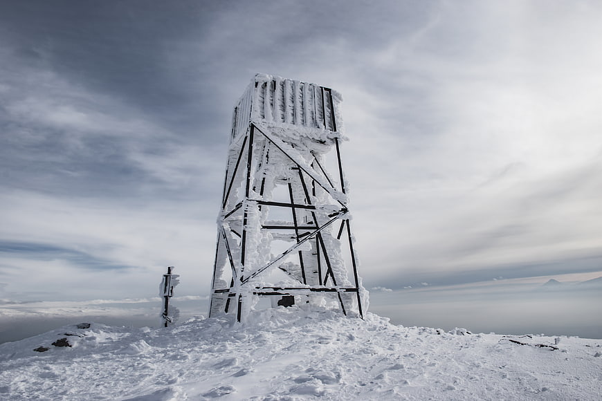 Snow-covered metal tower on mountain peak
