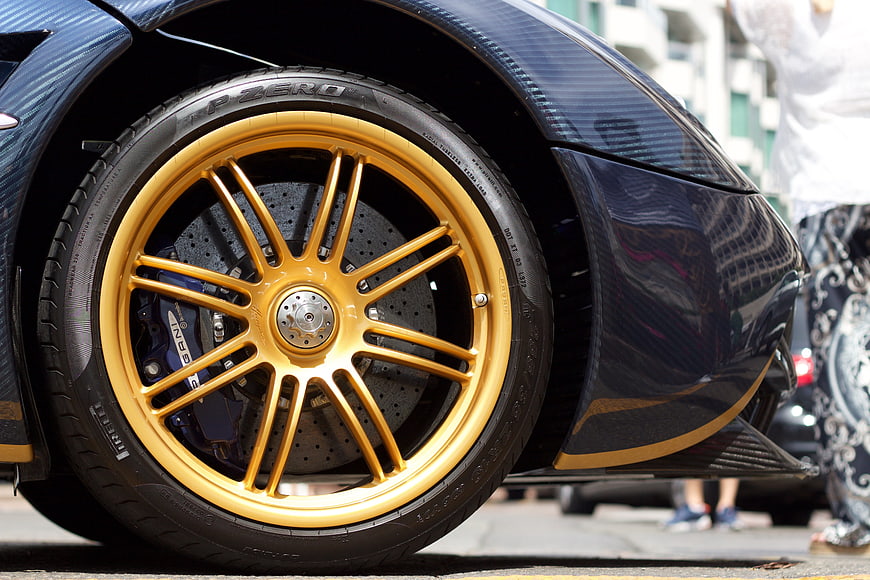 Close-up of gold Pagani Huayra wheel with carbon fiber body
