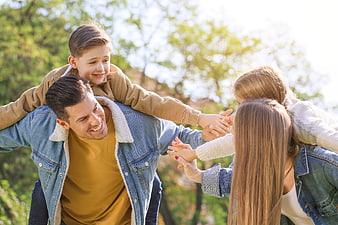 Happy family playing piggyback in sunny park