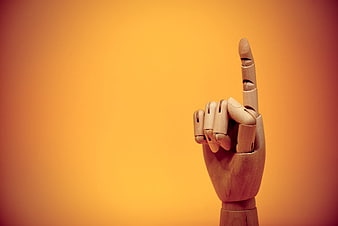 Wooden Mannequin Hand Pointing Up on Orange Background