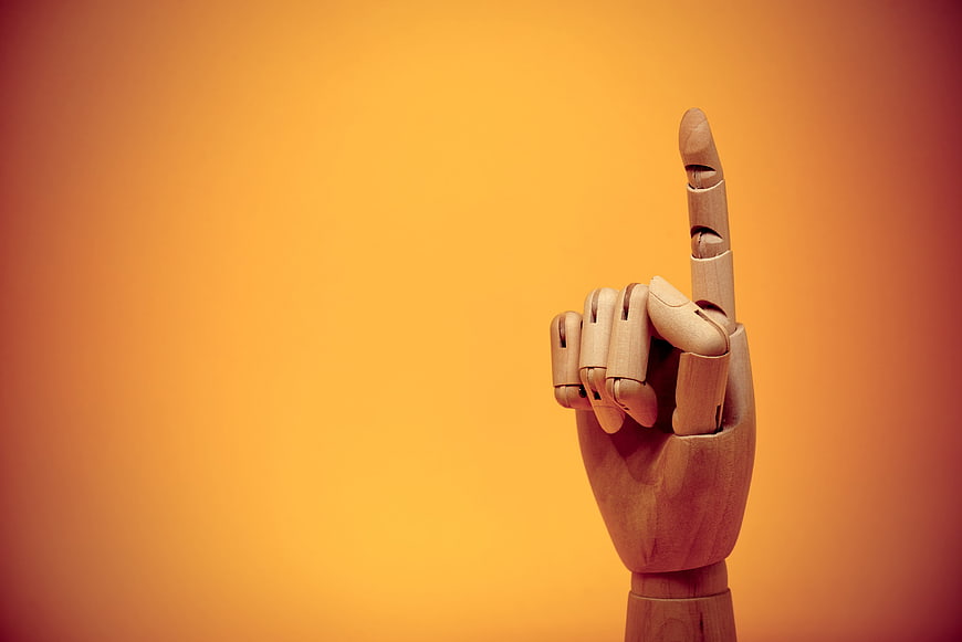Wooden Mannequin Hand Pointing Up on Orange Background