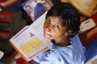 High angle portrait of young Indian schoolgirl reading book