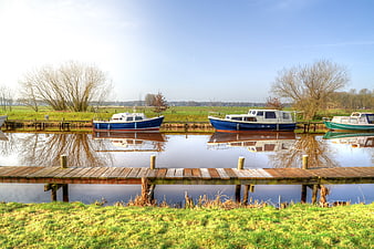 Blue and white boats docked in a calm canal with wooden pier