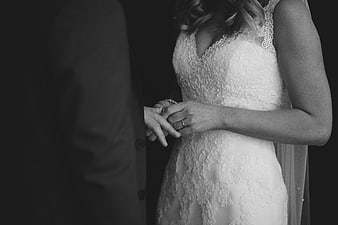 Black and white close-up of bride and groom holding hands