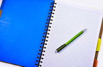 Green pen on graph paper notebook with blue cover