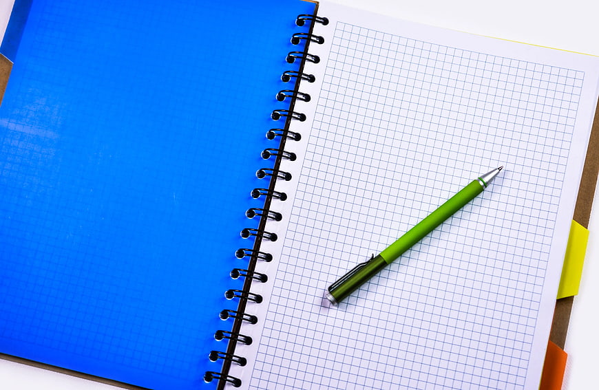Green pen on graph paper notebook with blue cover