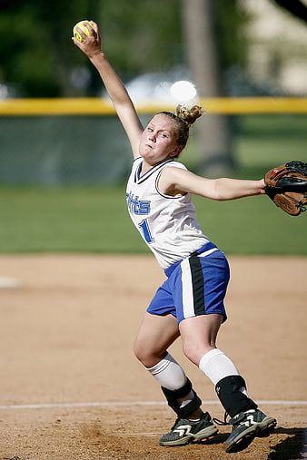 Female softball pitcher throwing ball on field