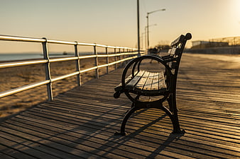 Empty wooden bench on boardwalk at golden hour sunset