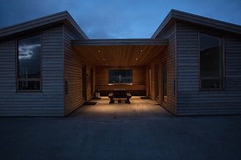 Modern wooden cabin exterior at dusk with warm lighting