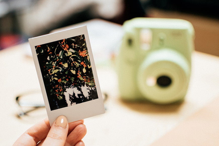 Hand holding instant photo with green camera background